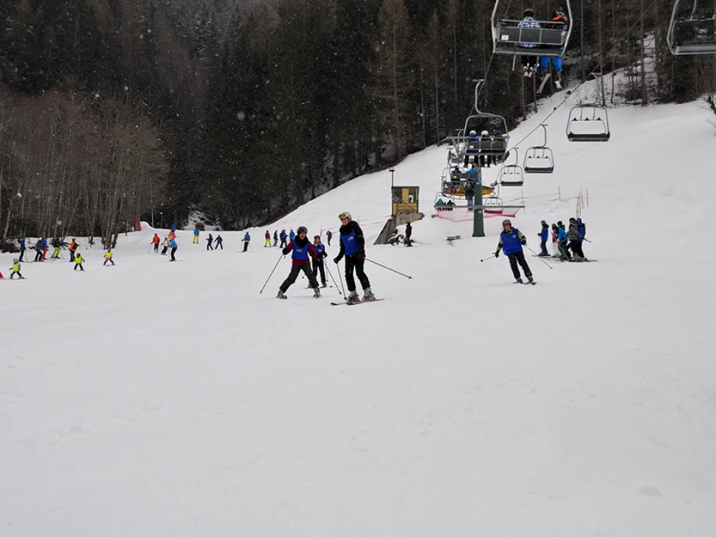 Blick über die Piste mit Sessellift und vielen Fahrenden.